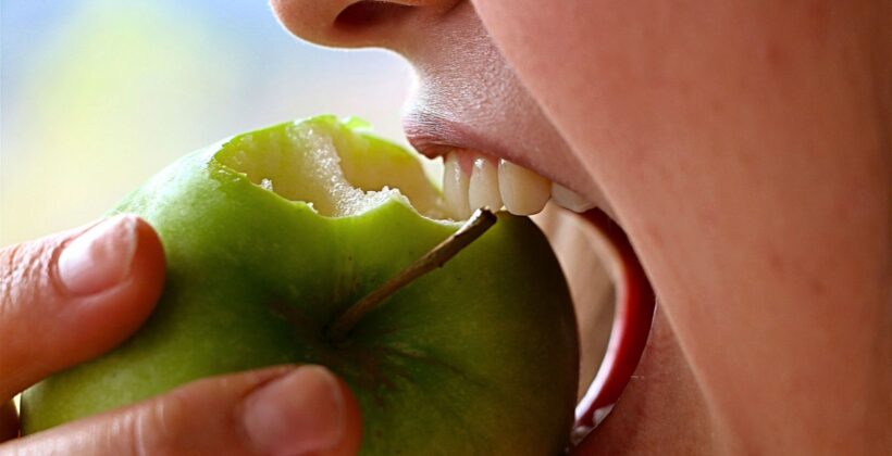 Person eating an apple - snacks that are good for your teeth, Midland Bay Dental.