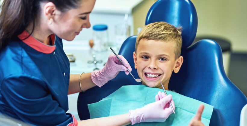 Boy smiling while sitting in dentist’s chair - dental care services - Midland Bay Dental.